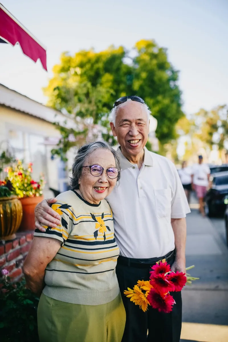 Happy senior couple smiling outdoors after better hearing care